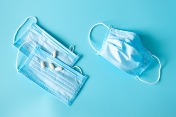 New and used protective face masks, pills and copy space on blue background. COVID epidemic. Flu and virus hygiene, top view