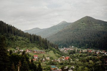 Fototapeta na wymiar village in a mountain valley amid mountain peaks with a growing dense coniferous forest