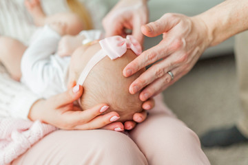 A beautiful young mother holds in her arms a small pretty blue-eyed 2-month-old daughter. Newborn.