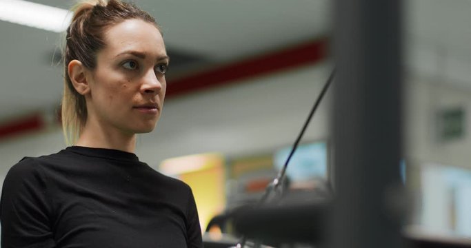 woman exercising with Cable triceps bar at gym.Rear view, slow motion. Woman training at triceps pushdown machine