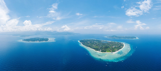 Amazing aerial view to Gili islands and Lombok. Unforgettable experience during vacations holidays. Blue sky and lagoon water. Clouds on the horizon. Air, Meno, Trawangan.