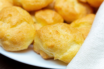 homemade profiteroles on a white plate close up