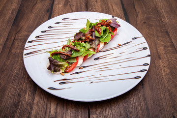 Caprese Salad With Fresh Tomatoes, Mozzarella Cheese, lettuce leaves, dried tomatoes and pine nuts.
