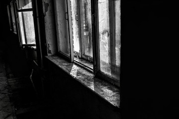 black and white photo with noise and film grain. abandoned hotel building. old broken windows. horror interior