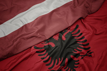 waving colorful flag of albania and national flag of latvia.