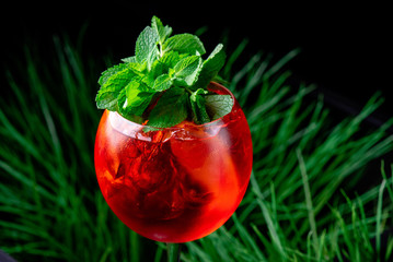Aperol spritz cocktail in a beautiful glass, decorated with mint on a background of fresh greens....
