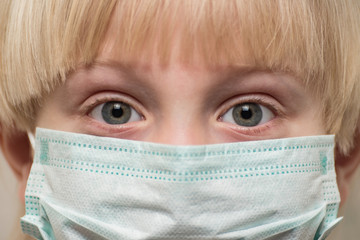 Сhild face in medical mask, close up. Frightened eyes of child in protective face mask