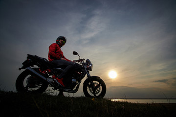 
young man with a motorcycle at sunset