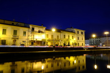 Fototapeta na wymiar Casa illuminata di notte e riflessa nel canale del mare, porto a Viareggio 