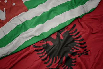 waving colorful flag of albania and national flag of abkhazia.