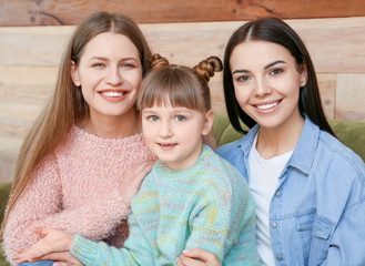Happy lesbian couple with little adopted girl at home