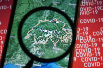 Switzerland country on google maps under magnifying glass with Red Covid-19 text Background. Selective Focus.    