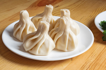 khinkali on a white plate  and fresh vegetables close-up. Dish of Georgian cuisine