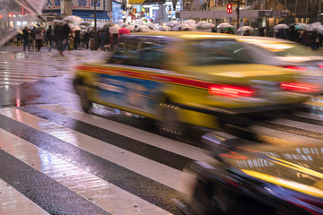 Yellow taxi passing through Shibuya Crossing in Tokyo on rainy night　雨の夜...