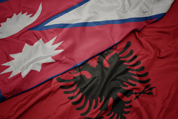waving colorful flag of albania and national flag of nepal.