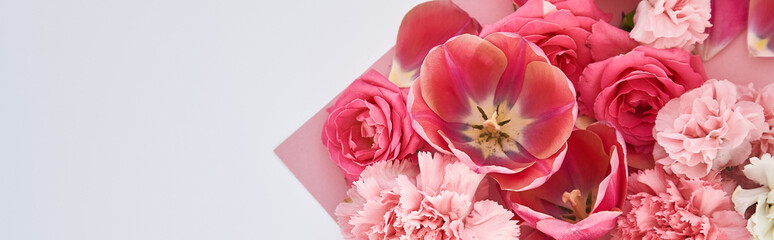 Fototapeta na wymiar top view of roses, tulips and carnations on pink and white background, panoramic shot