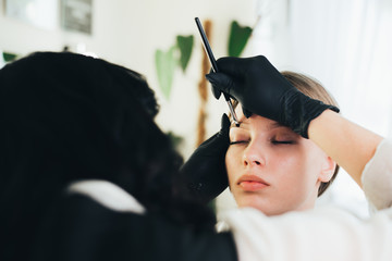 Dyeing and shaping of eyebrows. girl in a beauty salon.eyebrow coloring henna brush tool