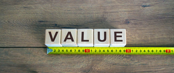 Value word on cubes arranged behind the ruler on wooden table.