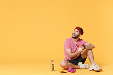Funny fitness sporty guy sportsman in headband t-shirt in home gym isolated on yellow background....