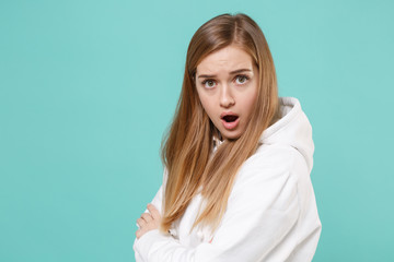 Side view of shocked young woman girl in casual white hoodie posing isolated on blue turquoise...
