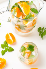 glass with a drink with orange mint and ice on the table
