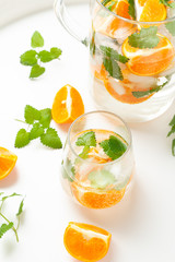 carafe and glass with a drink with orange mint and ice
