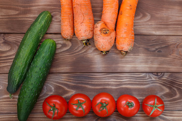 Flatley cucumbers, tomatoes and carrots on a wooden background