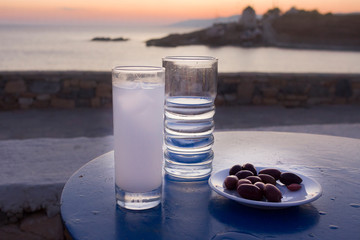 Ouzo glass with ice, water and olives meze on sea after the sunset background. Taken in Koufonissia...
