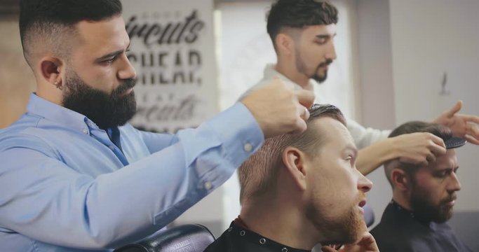 Professional barbers working with clients in barber shop