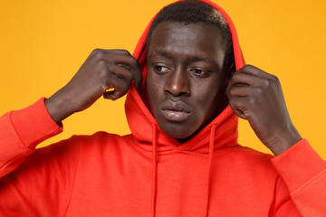 Close up of young african american man guy in red streetwear hoodie with hood on head posing...