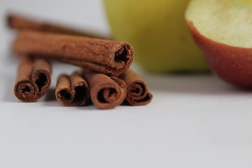 five or more sticks of cinnamon stevia lie together near apples on a white background still life