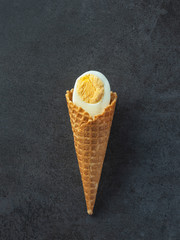 boiled egg in waffle cone in vertical frame on dark background