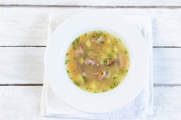 Pea soup with smoked meat and potato in white plate