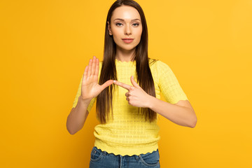 Attractive girl using sign in deaf and dumb language on yellow background