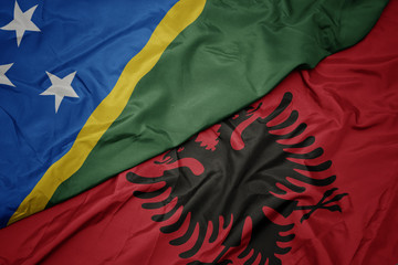 waving colorful flag of albania and national flag of Solomon Islands .