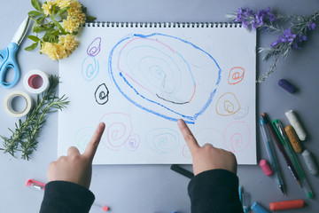 画用紙に絵を描くこどもの小さな手