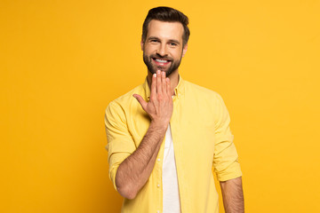 Smiling man looking at camera while showing word speak in sign language on yellow background