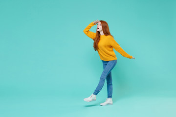 Shocked young redhead woman girl in yellow sweater posing isolated on blue turquoise wall background. People lifestyle concept. Mock up copy space. Holding hand at forehead looking far away distance.