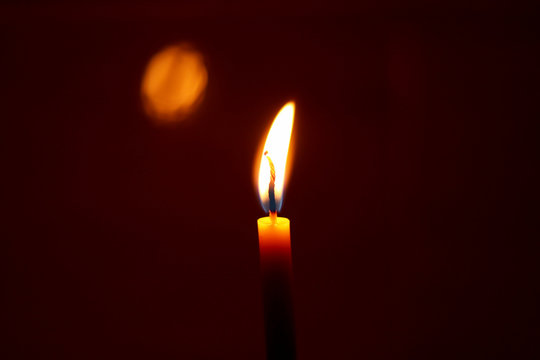 Candle fire light or glowing candlelight bright in night, used in Halloween mourning loss death memorial and memorial  on black dark background. soft fosus and color tone.