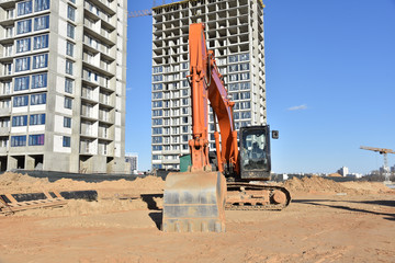 Excavator working at construction site on earthworks. Backhoe on road work digs ground. Paving out...