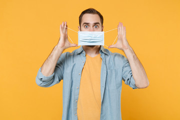 Shocked young man in casual clothes isolated on yellow background studio portrait. Epidemic...