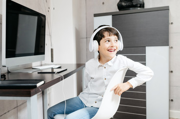 A little boy wearing a white shirt holding for a photo with white headphones