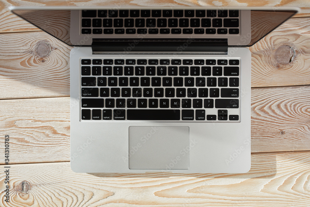 Aufkleber Top view of laptop on loft-style table in sunny day. Coworking or working at home concept image.