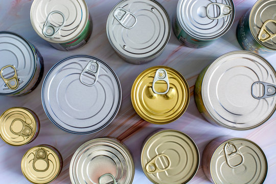Overhead view various closed tin cans with food preserves. Canned food in different sizes and colors. Stock non-perishable preserved food