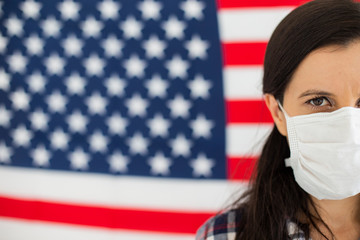 American young woman wearing coronavirus mask with the flag of the United States in the background