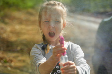 Adorable little girl playing with water gun on hot summer day. Cute child having fun with water outdoors. Funny summer games for kids.