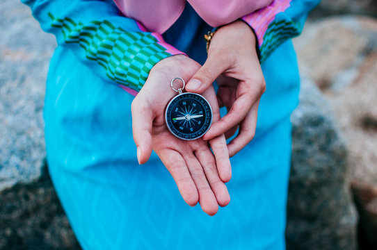 Midsection Of Woman Holding Navigational Compass At Beach Against Sky