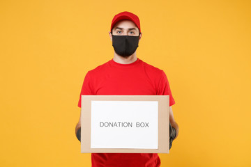 Delivery man employee in red cap blank t-shirt uniform face mask glove hold donations cardboard box isolated on yellow background studio Service quarantine pandemic coronavirus virus 2019-ncov concept