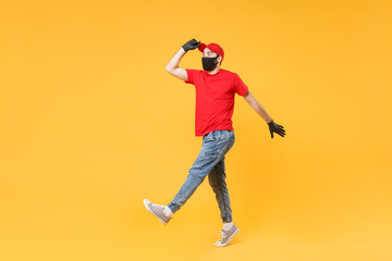 Fototapeta na wymiar Full length delivery man in red cap t-shirt uniform sterile face mask gloves isolated on yellow background studio Guy employee courier Service quarantine pandemic coronavirus virus 2019-ncov concept.