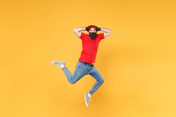 Fototapeta na wymiar Fun jumping delivery man in red cap t-shirt uniform sterile face mask gloves isolated on yellow background studio Guy employee courier Service quarantine pandemic coronavirus virus 2019-ncov concept.